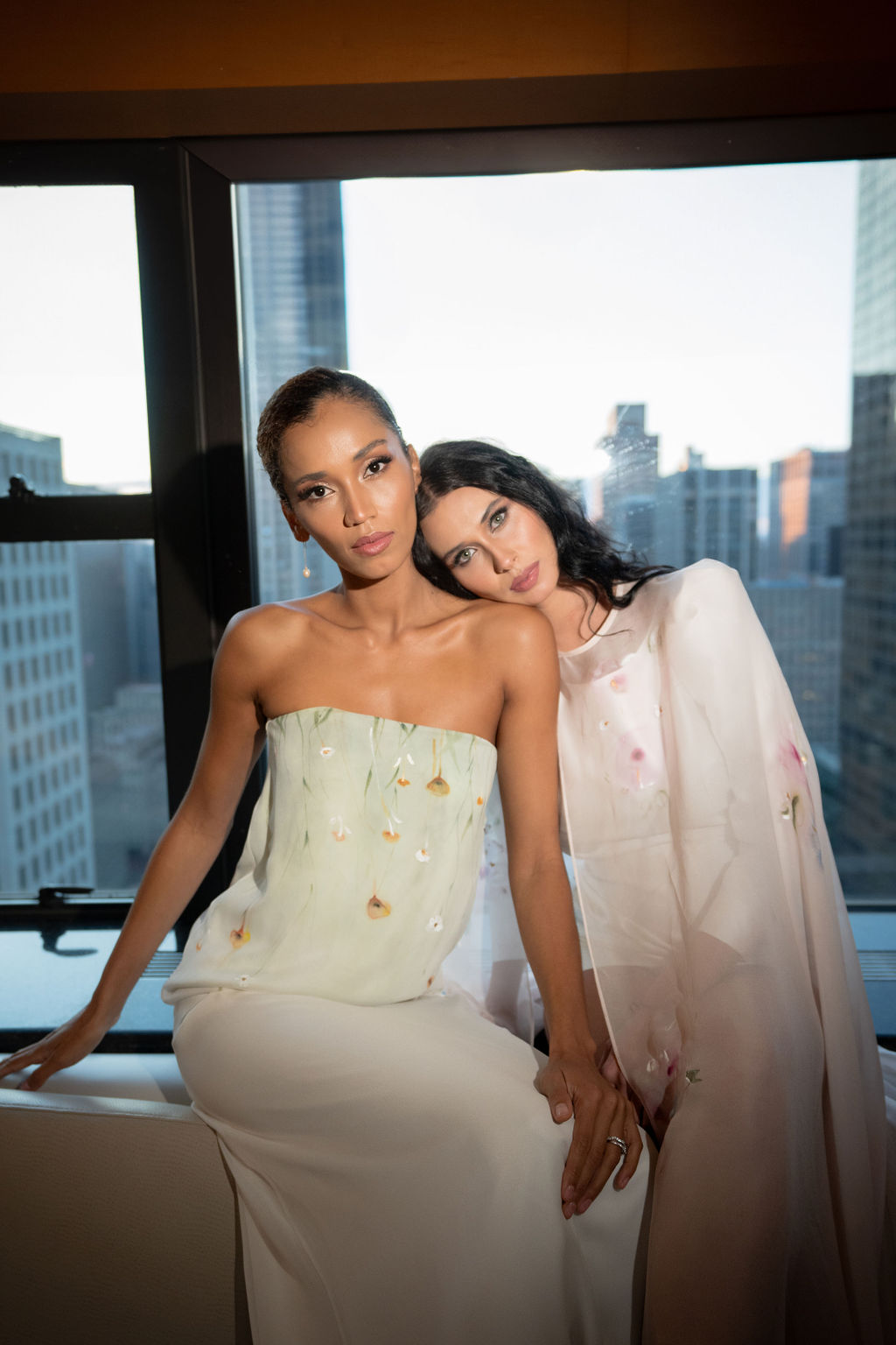 two models sitting in artistic bridal couture with hand painted florals