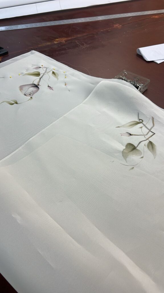 hand painted silk is lying flat on cutting table, ready top ready to be stitched